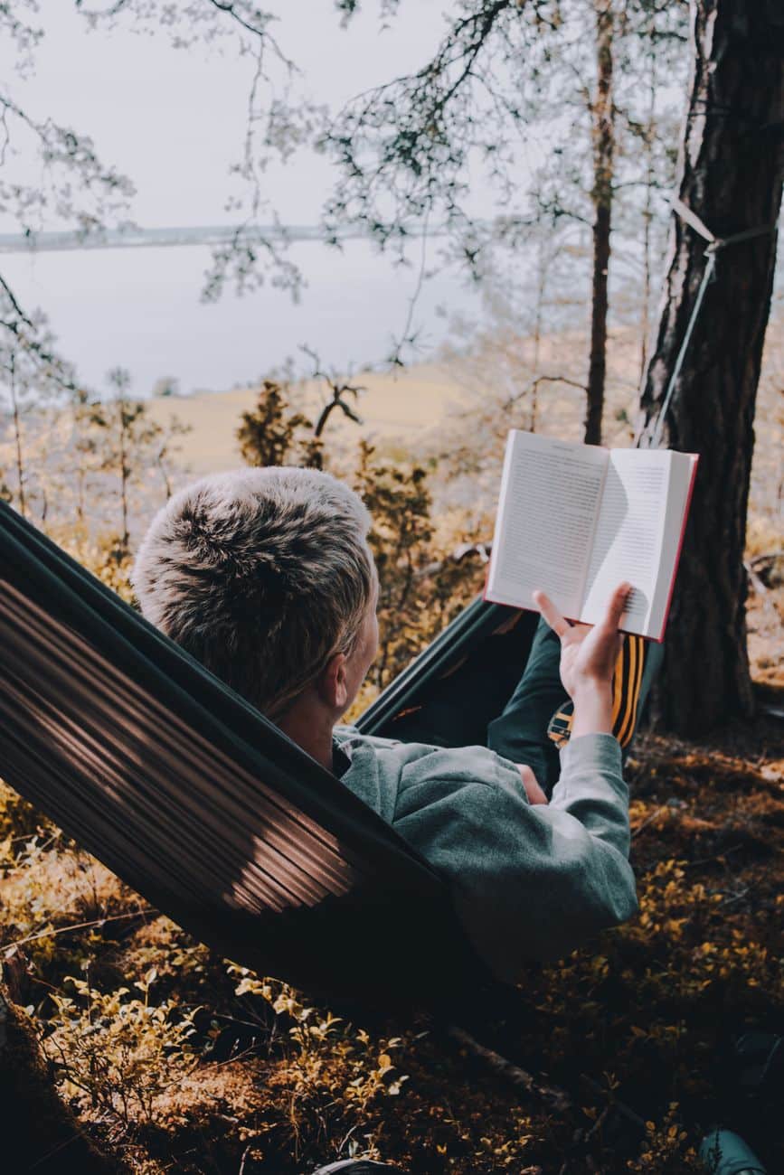 woman reading a book on a hammock