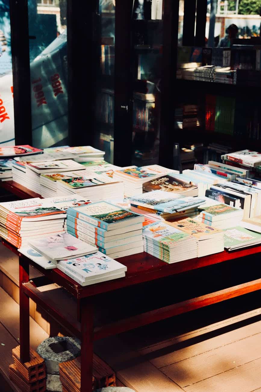 stacks of books on sunlit table in a bookstore